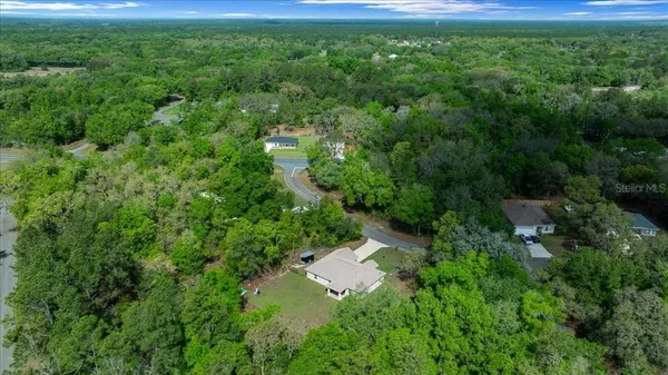 an aerial view of residential house with outdoor space and trees all around