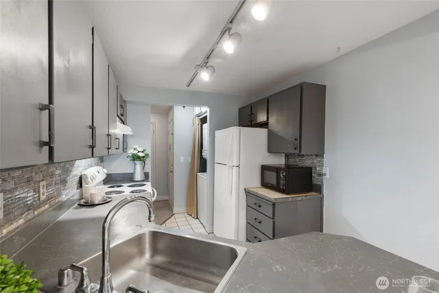 a kitchen with stainless steel appliances kitchen island granite countertop a refrigerator and a sink