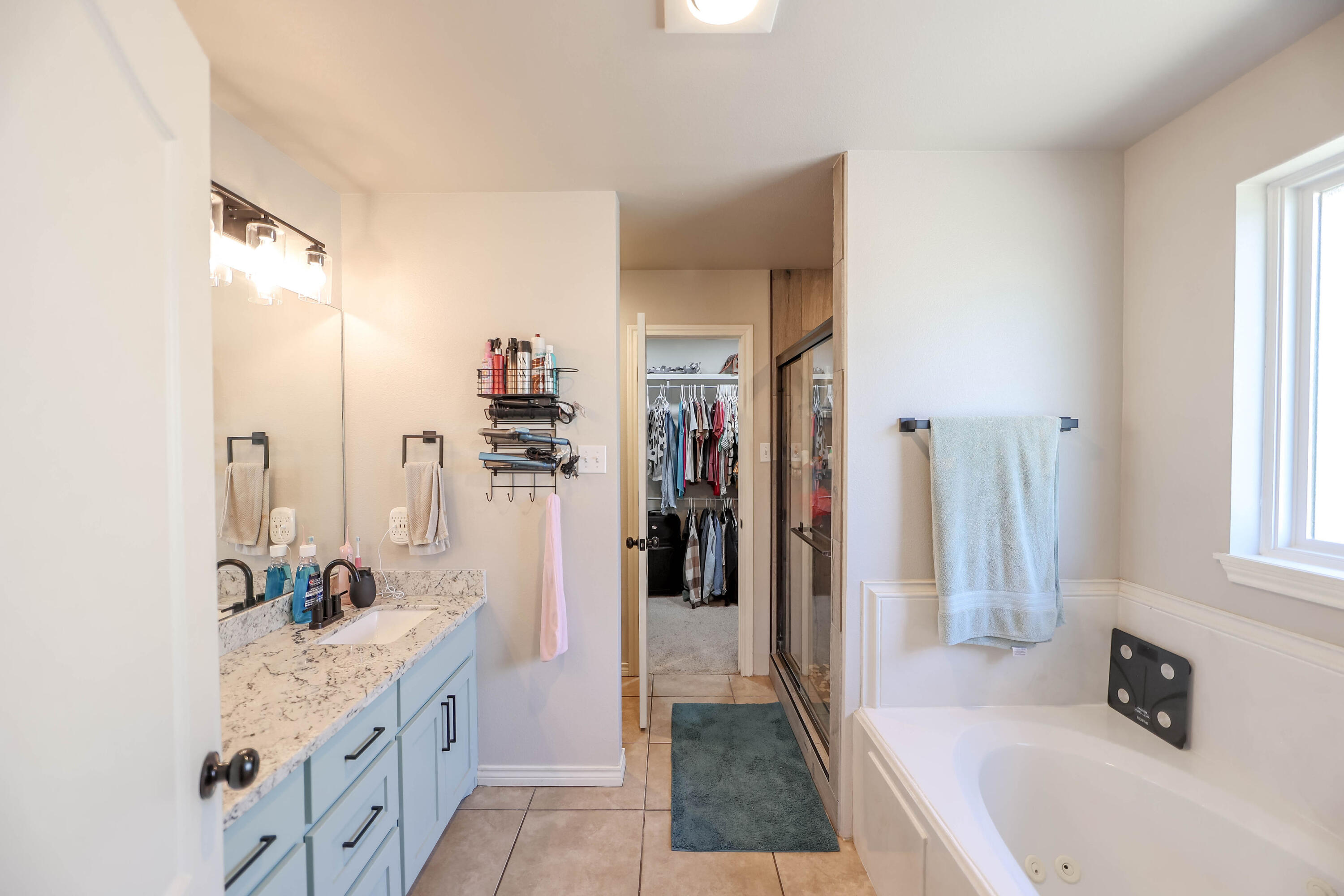 6008 103rd Street Lubbock, TX 79424 - Photo 14 of 29 a bathroom with a tub sink a mirror and shower