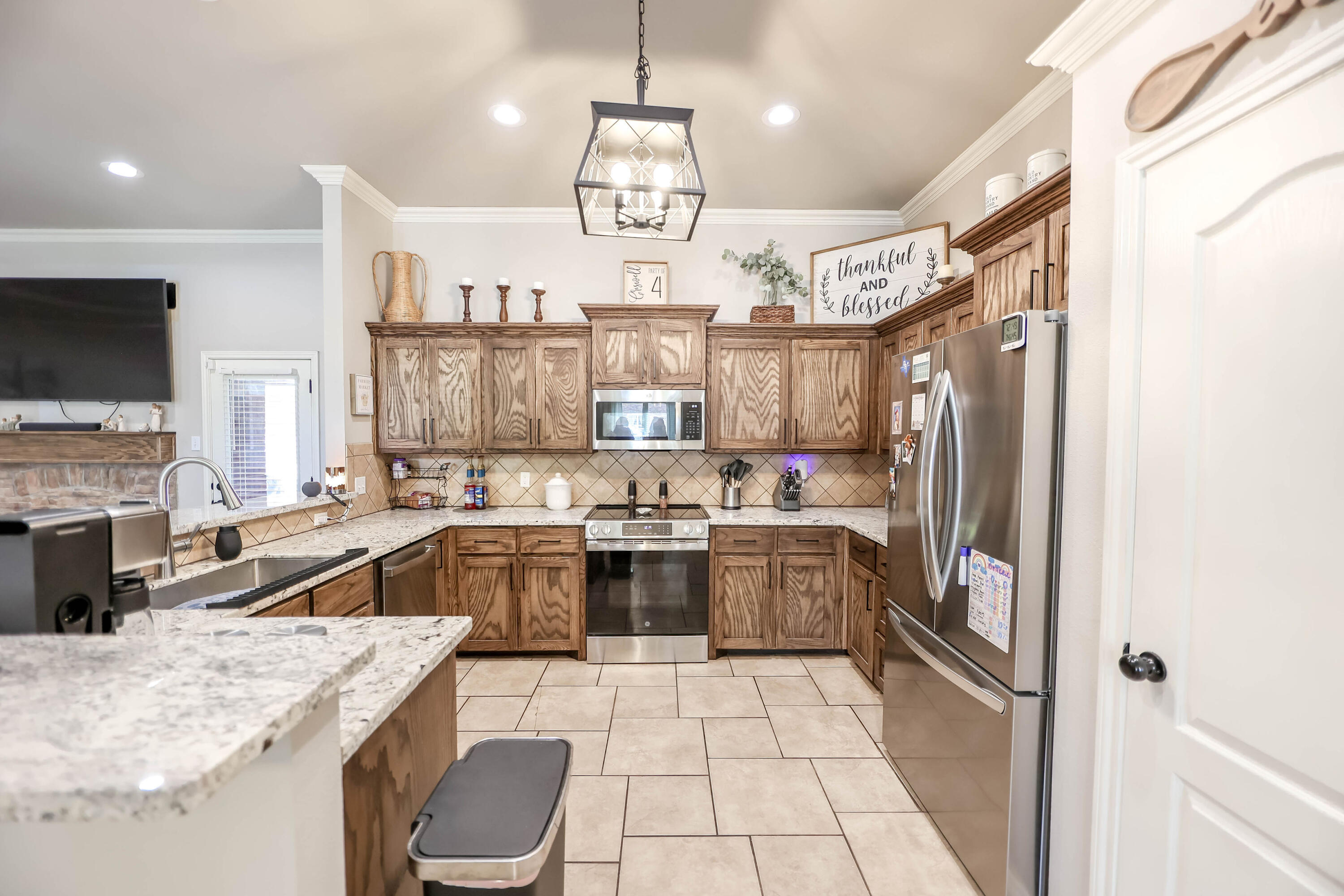 6008 103rd Street Lubbock, TX 79424 - Photo 7 of 29 a kitchen with a sink a counter top space stainless steel appliances and a chandelier