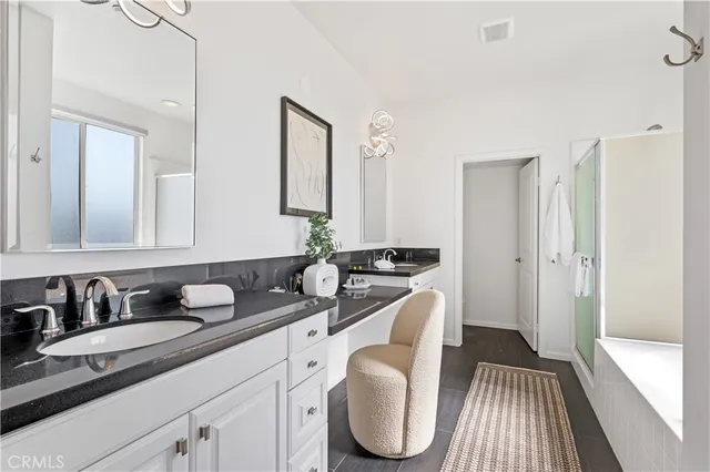 a en suite bathroom with a granite countertop sink and a mirror