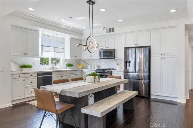 a kitchen with stainless steel appliances a dining table chairs stove refrigerator and microwave