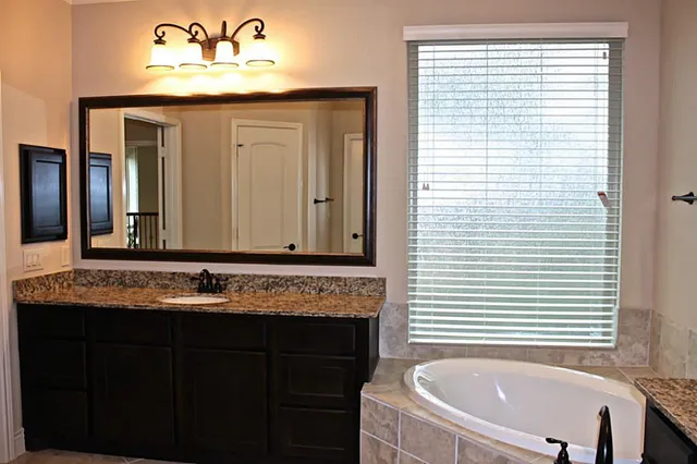 a bathroom with a granite countertop sink and a bathtub