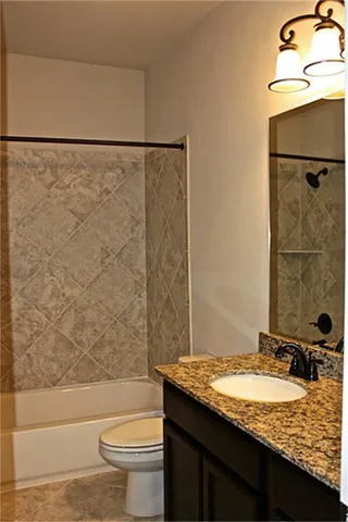 a bathroom with a granite countertop bathtub shower sink and toilet