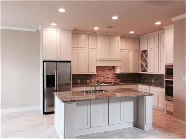 a kitchen with kitchen island granite countertop a sink a center island stainless steel appliances and cabinets