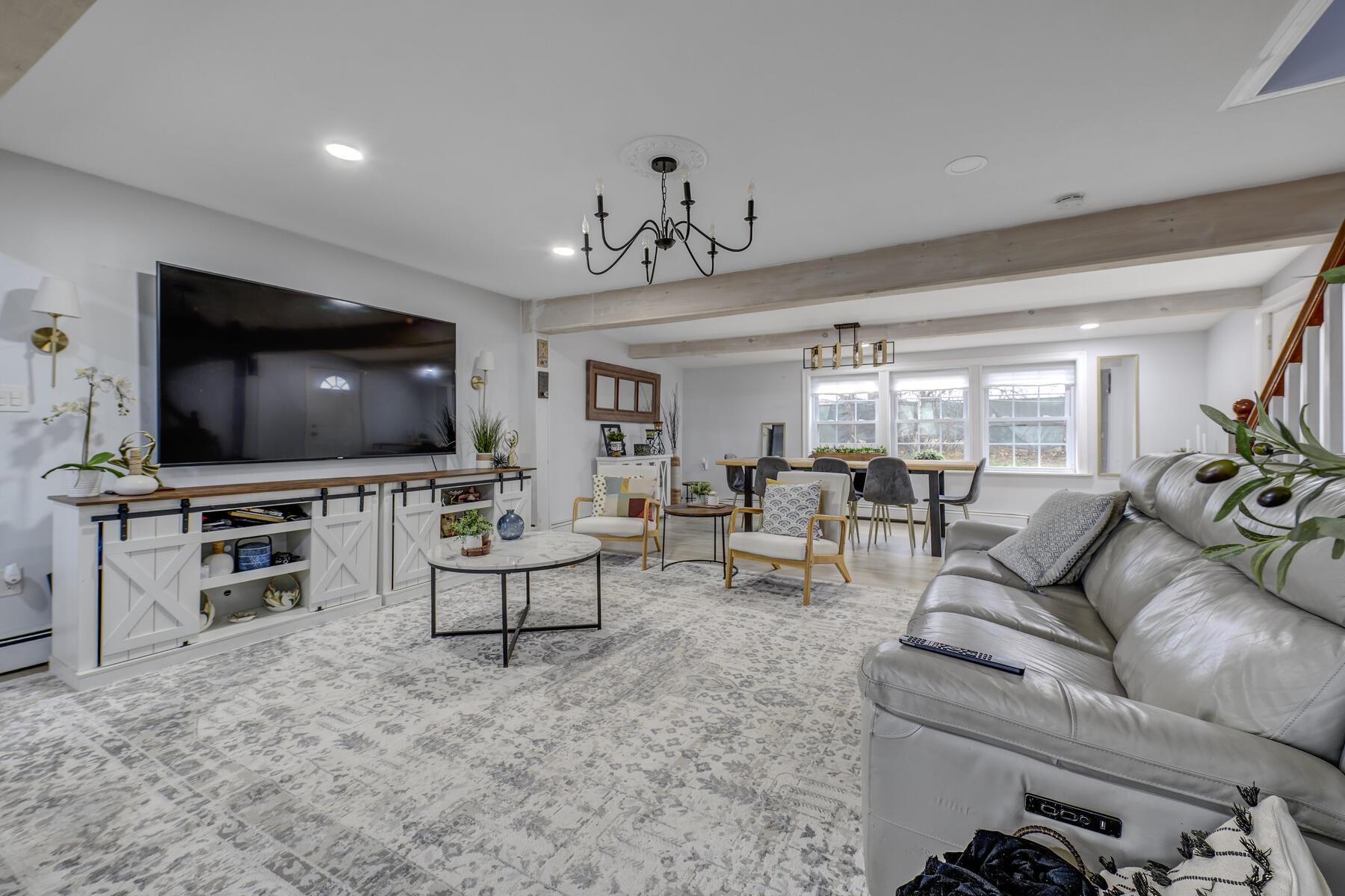 Living area with beamed ceiling, recessed lighting, and a notable chandelier