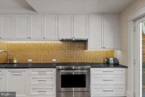 a kitchen with granite countertop white cabinets and stainless steel appliances