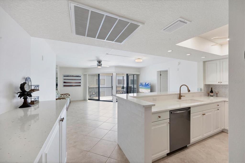 2810 North Beach Road, Unit D205 Englewood, FL 34223 - Photo 8 of 48 a large white kitchen with a sink and dishwasher a stove with wooden floors