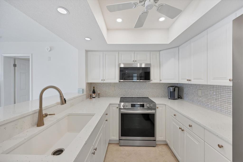 2810 North Beach Road, Unit D205 Englewood, FL 34223 - Photo 9 of 48 a kitchen with stainless steel appliances sink a stove and cabinets