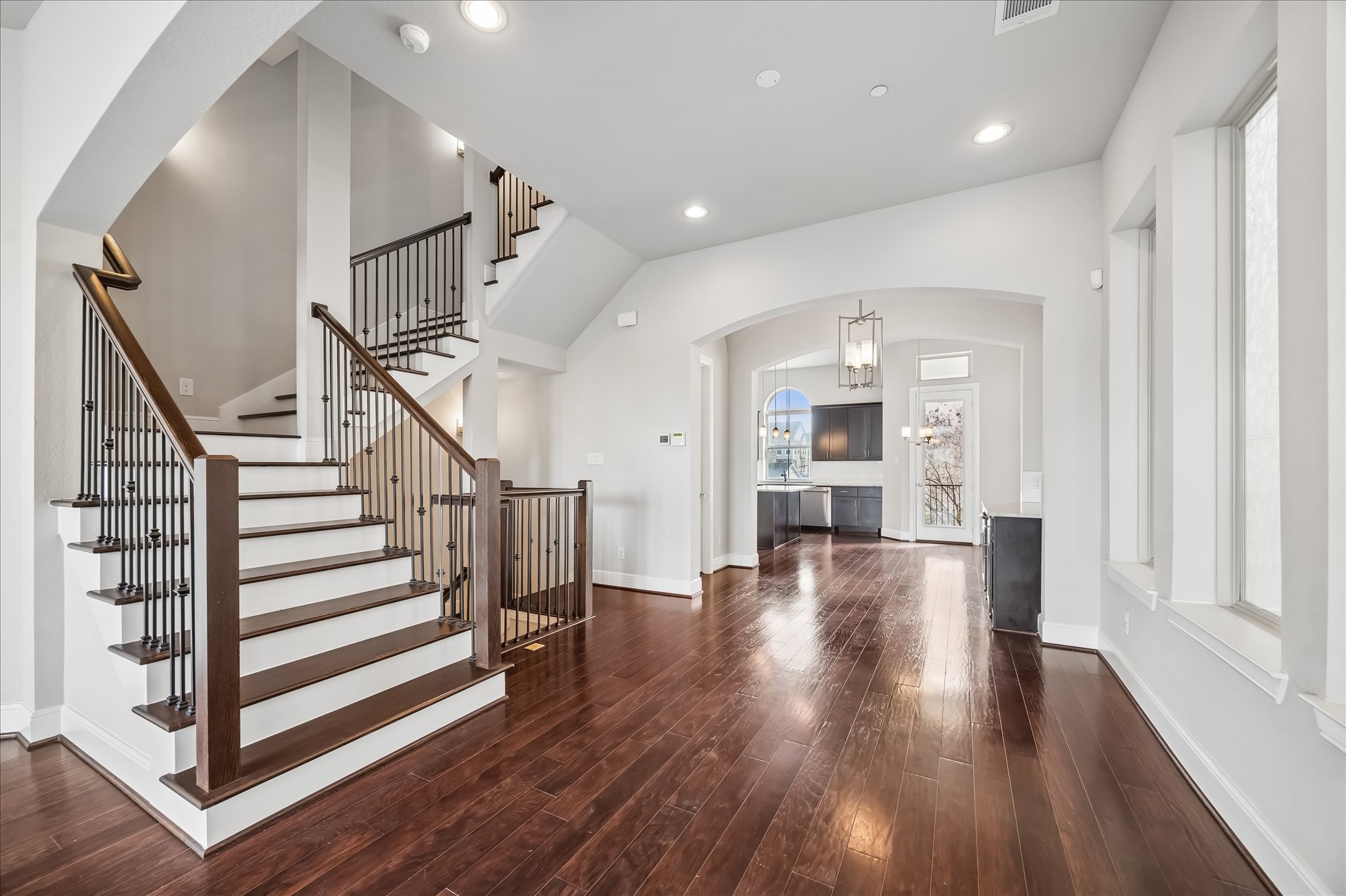 4016 Barnes Street Houston, TX 77007 - Photo 12 of 37 a view of a hallway with wooden floor staircase and a kitchen