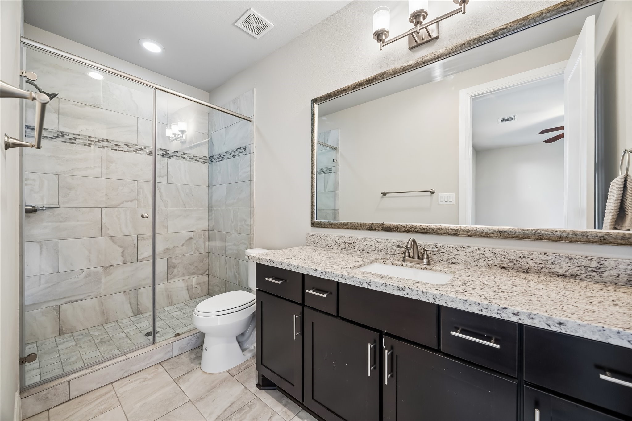 4016 Barnes Street Houston, TX 77007 - Photo 10 of 37 a bathroom with a granite countertop sink a toilet a mirror and shower
