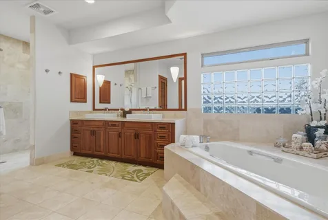 a spacious bathroom with a double vanity sink mirror and bathtub