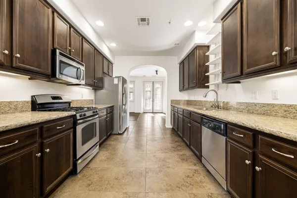 a large kitchen with stainless steel appliances granite countertop a lot of counter space and wooden cabinets