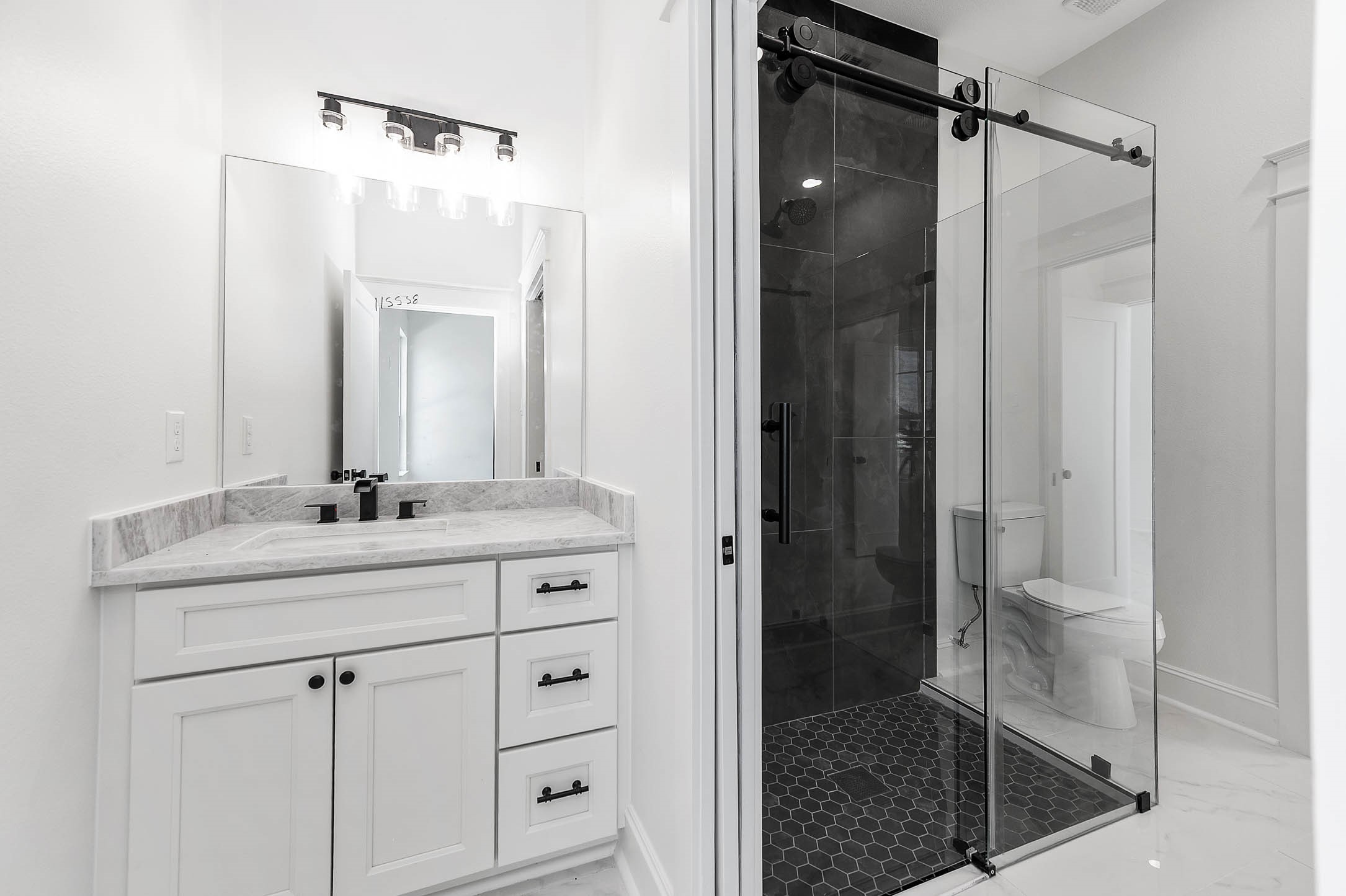 13911 Routt Point Road Needville, TX 77461 - Photo 10 of 19 Modern bathroom featuring a sleek vanity, glass-enclosed walk-in shower, bold tile, and black finishes throughout.