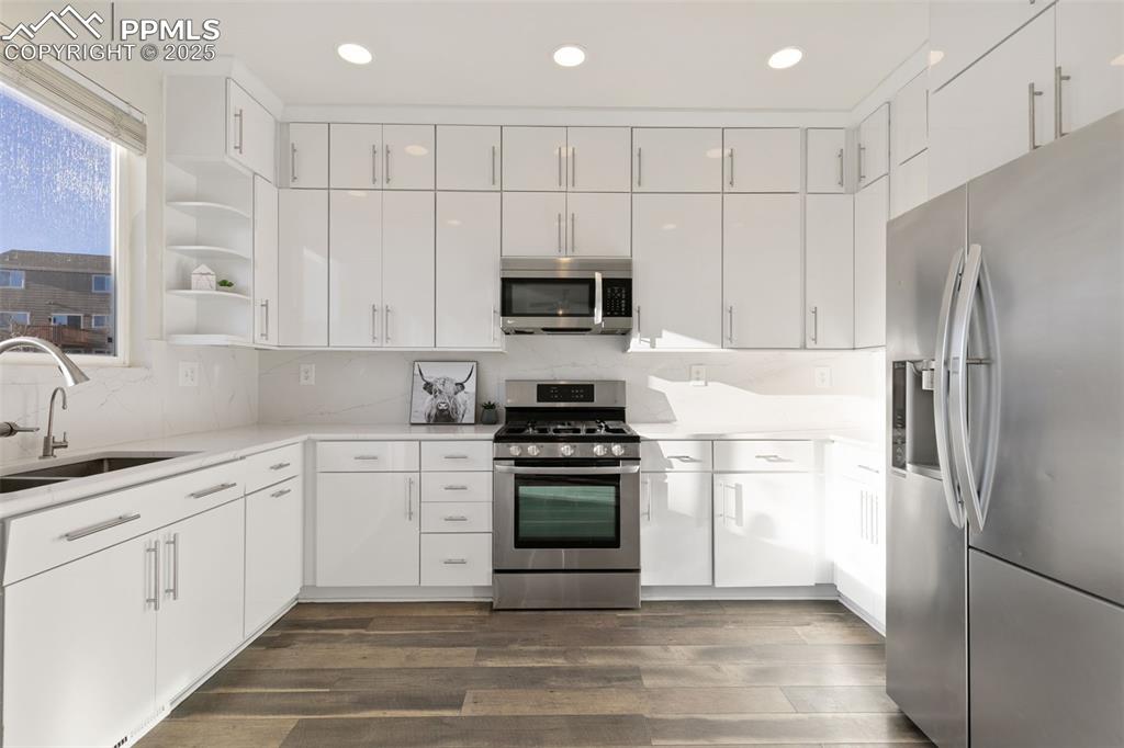 9202 Ballybunion Road Peyton, CO 80831 - Photo 13 of 36 a kitchen with granite countertop white cabinets and stainless steel appliances