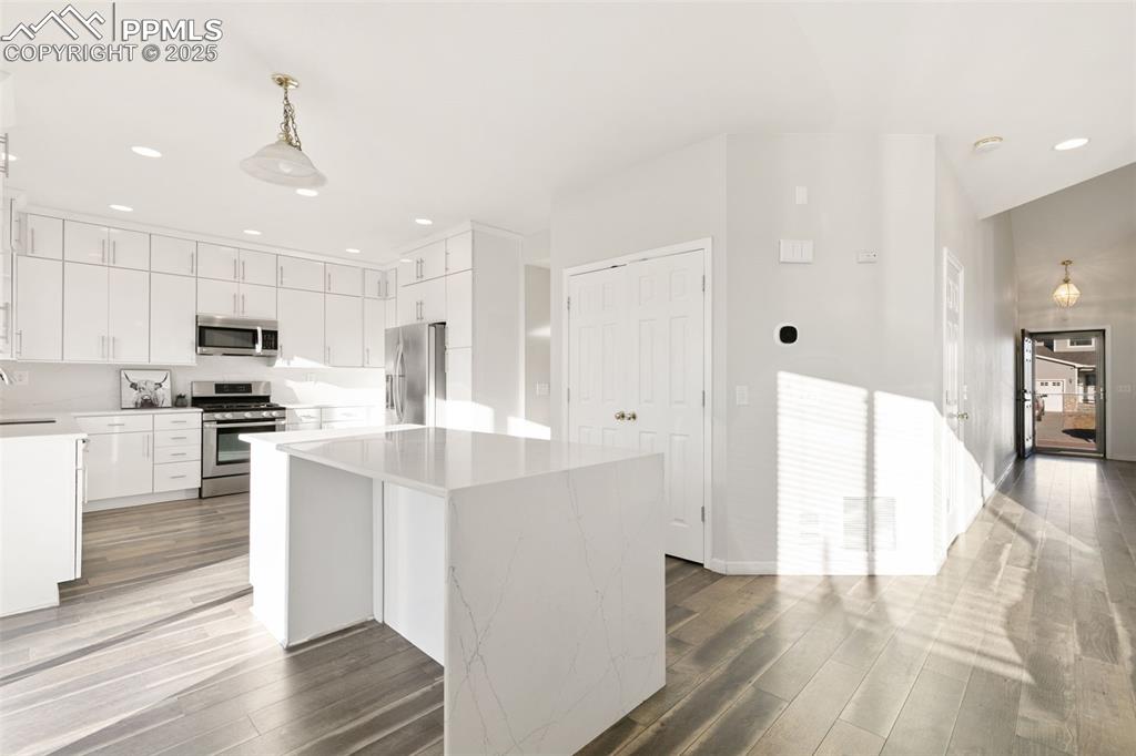 9202 Ballybunion Road Peyton, CO 80831 - Photo 14 of 36 a kitchen with stainless steel appliances kitchen island hardwood floor sink and stove