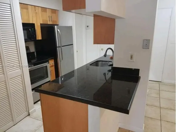 a kitchen with granite countertop a refrigerator and a sink