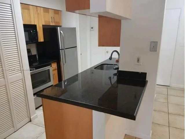 a kitchen with granite countertop a refrigerator and a sink
