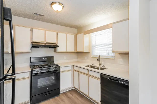 a kitchen with a sink appliances cabinets and a window