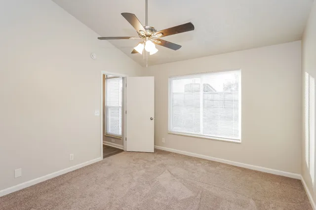 an empty room with window and ceiling fan