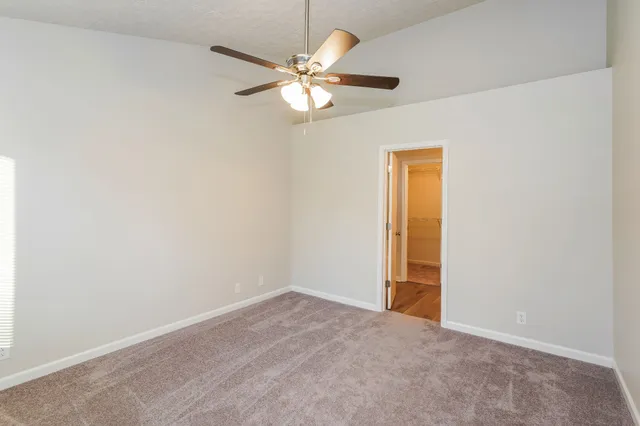 an empty room with a chandelier fan and windows