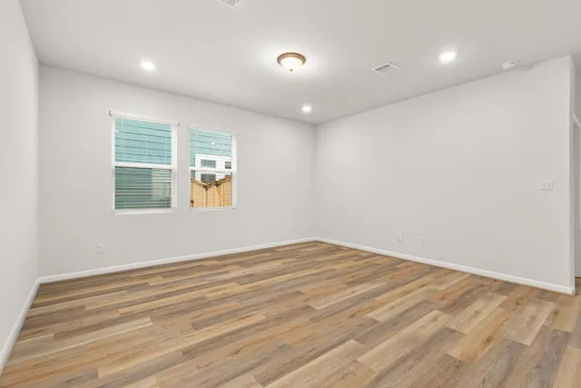 an empty room with wooden floor and windows