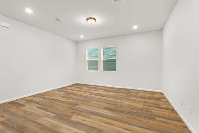 an empty room with wooden floor and windows