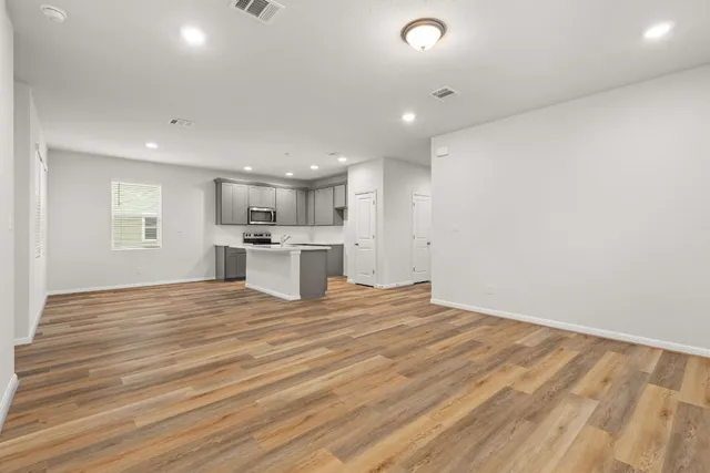 a view of kitchen and empty room with wooden floor