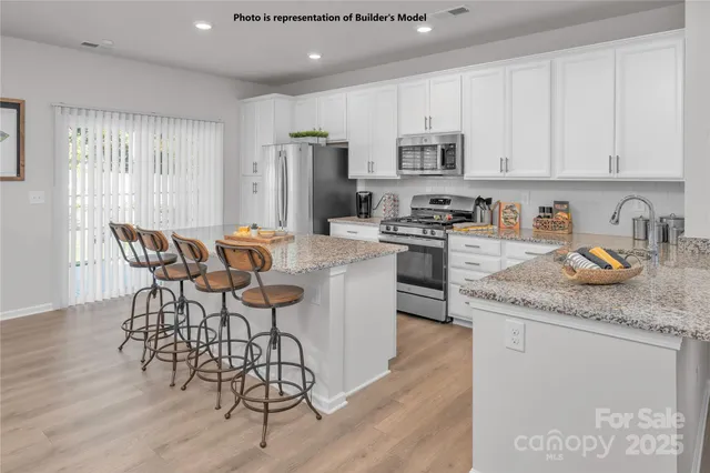 a kitchen with stainless steel appliances granite countertop a table chairs microwave and sink