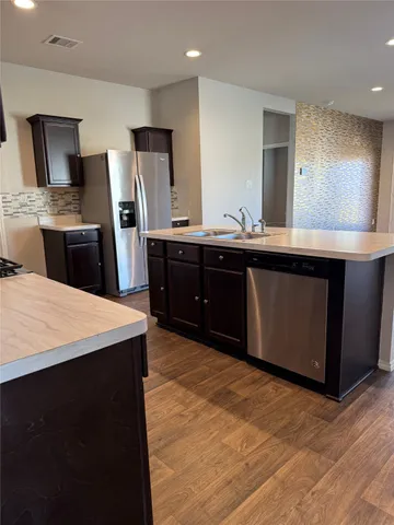 a kitchen with stainless steel appliances granite countertop a stove a sink dishwasher a refrigerator and a oven with wooden floor