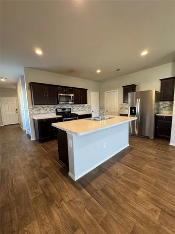 a large kitchen with stainless steel appliances granite countertop a stove a sink dishwasher and a microwave oven on the wooden floor