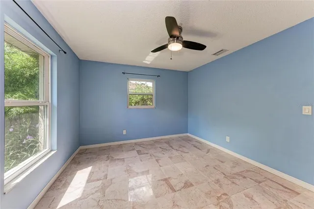 an empty room with a window and a ceiling fan