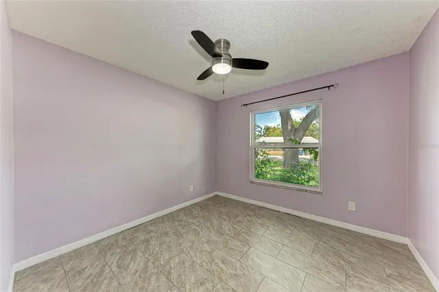 an empty room with windows and ceiling fan