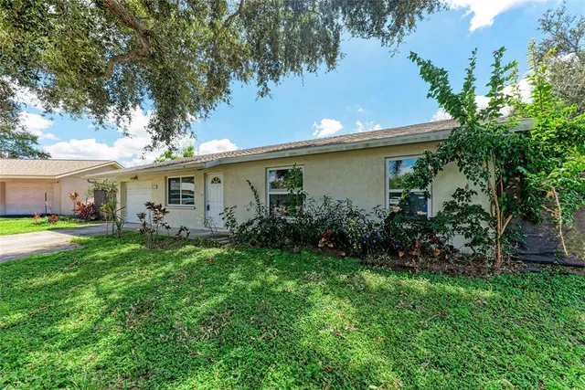 a view of a white house with a tree in the middle