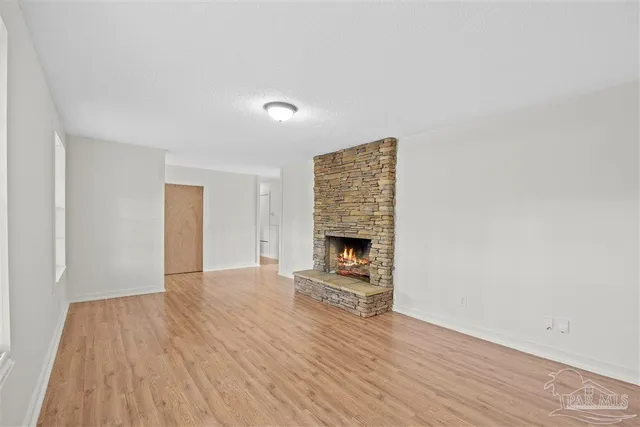a view of empty room with wooden floor and fireplace