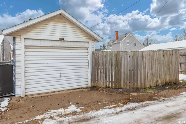 a view of a grey house with wooden fence