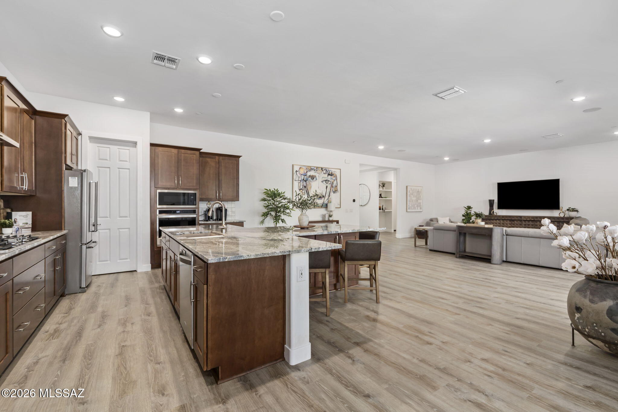 12791 East Tortoise Pointe Drive Vail, AZ 85641 - Photo 16 of 50 a large kitchen with stainless steel appliances refrigerator a microwave a stove and a dining table with wooden floor