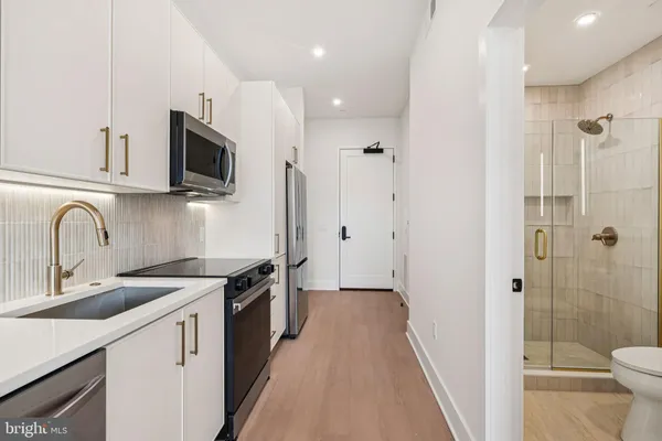 a view of a kitchen with a sink and dishwasher with wooden floor