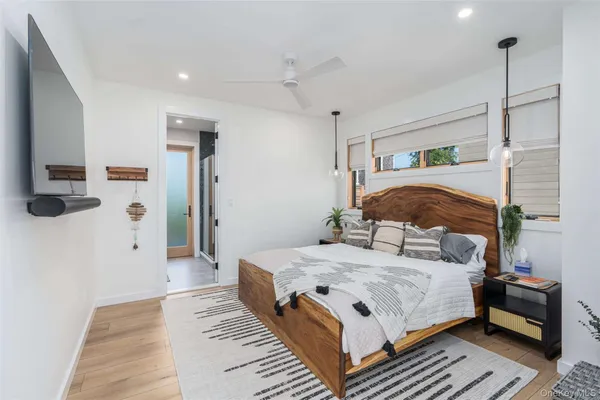 a bedroom with a bed wooden floor and flat screen tv