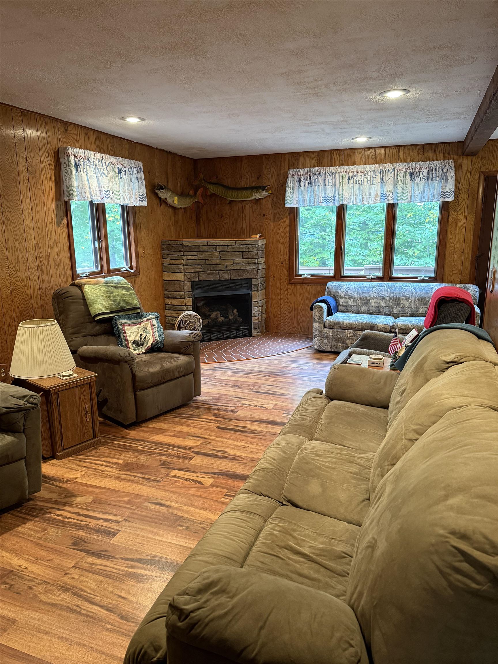 63380 Trout Lake Road Iron River, WI 54847 - Photo 12 of 36 Living area featuring wood walls, wood finished floors, a fireplace, and a textured ceiling