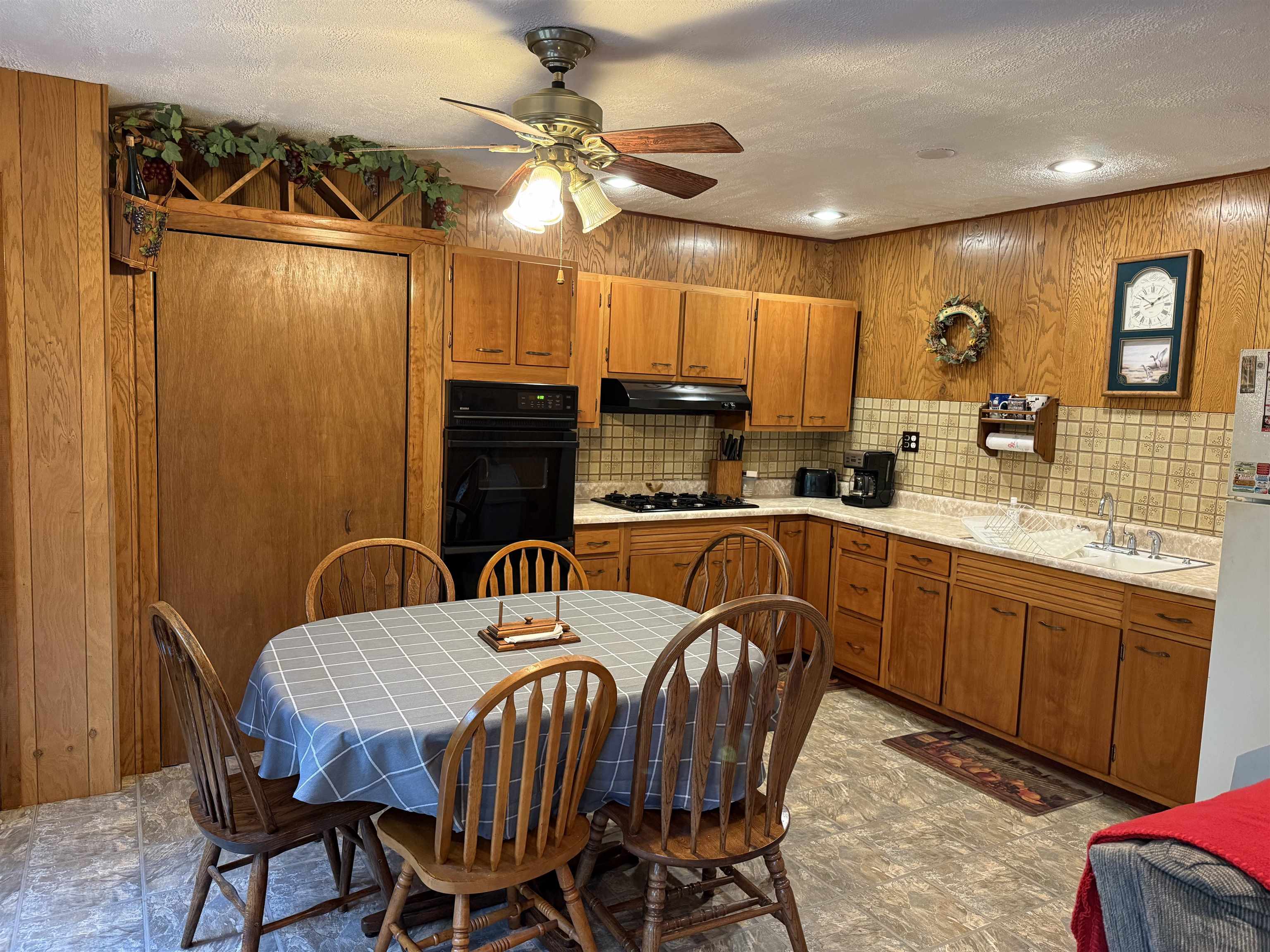 63380 Trout Lake Road Iron River, WI 54847 - Photo 14 of 36 Kitchen featuring brown cabinetry, black appliances, tasteful backsplash, a ceiling fan, and a textured ceiling