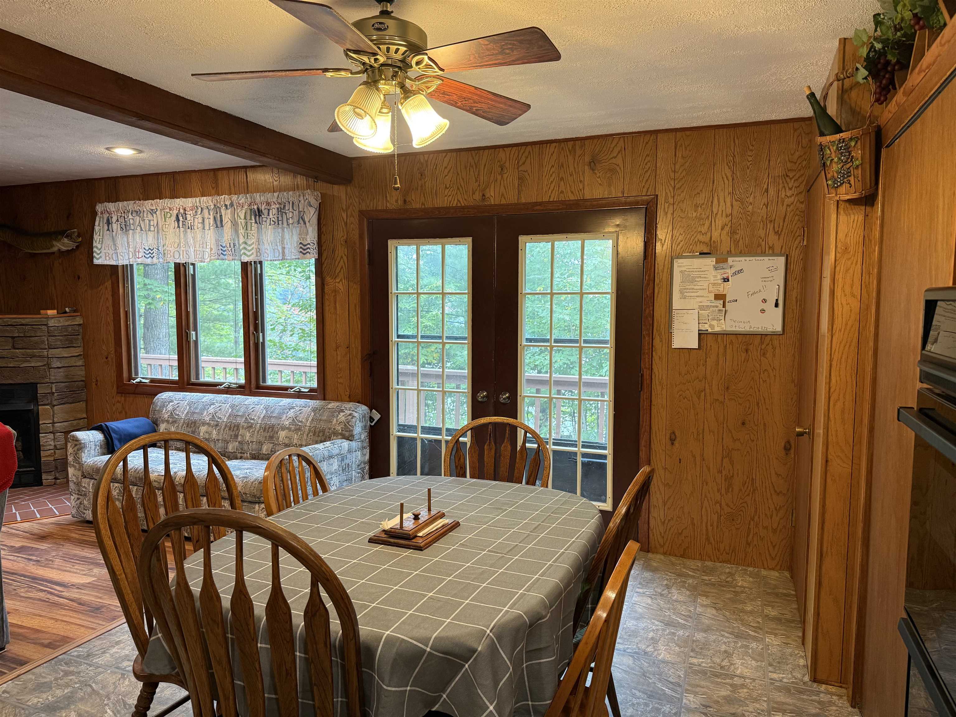 63380 Trout Lake Road Iron River, WI 54847 - Photo 15 of 36 Dining space featuring wood walls, beam ceiling, a ceiling fan, a fireplace, and french doors