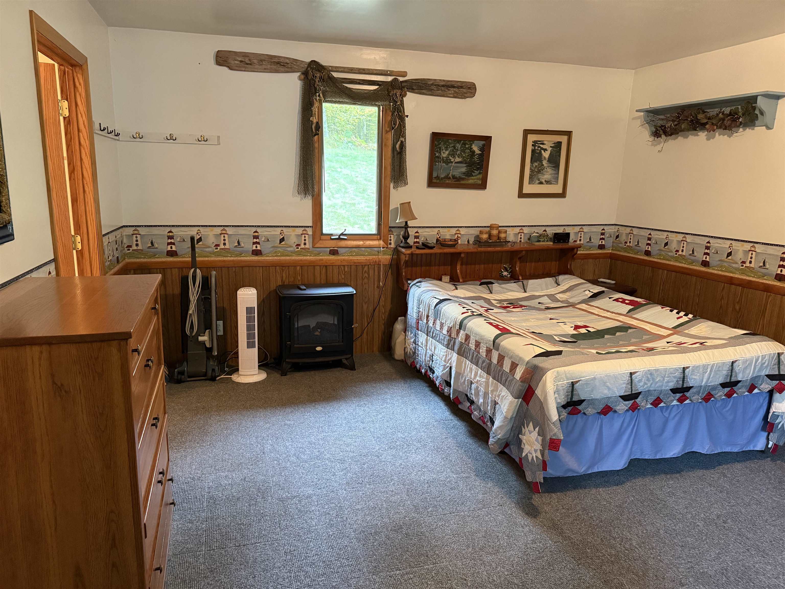 63380 Trout Lake Road Iron River, WI 54847 - Photo 17 of 36 Bedroom featuring a wainscoted wall, carpet flooring, a wood stove, and wood walls