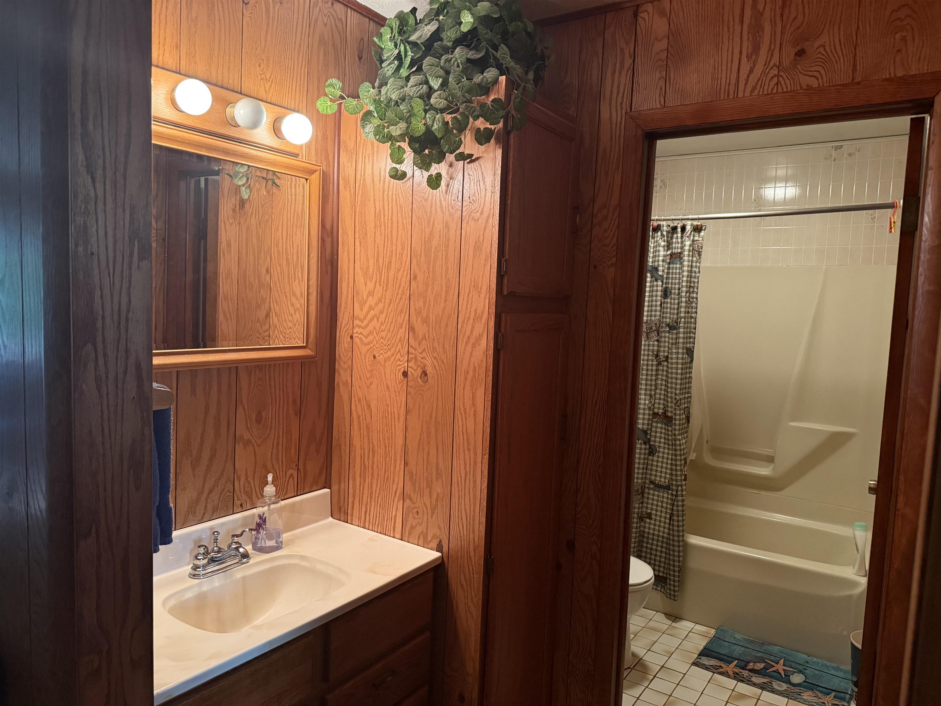 63380 Trout Lake Road Iron River, WI 54847 - Photo 27 of 36 Full bathroom featuring vanity, shower / bath combination with curtain, light tile patterned flooring, and wooden walls