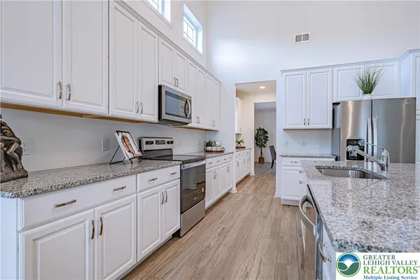 a large kitchen with stainless steel appliances granite countertop a stove a sink dishwasher and a refrigerator with wooden floor