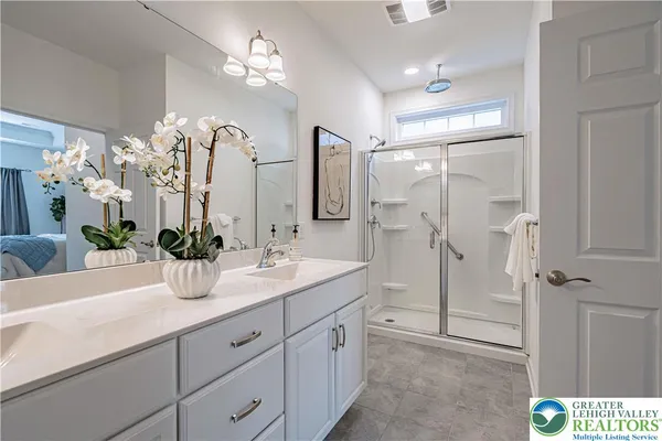 a bathroom with a double vanity sink mirror and shower