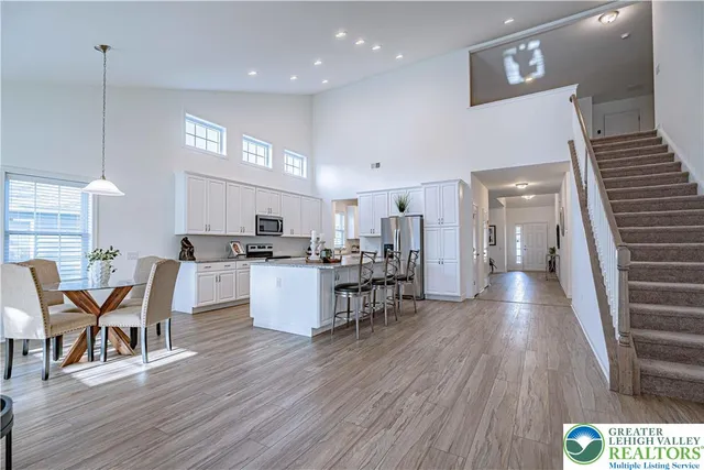 a open kitchen with stainless steel appliances kitchen island granite countertop a table chairs and a refrigerator