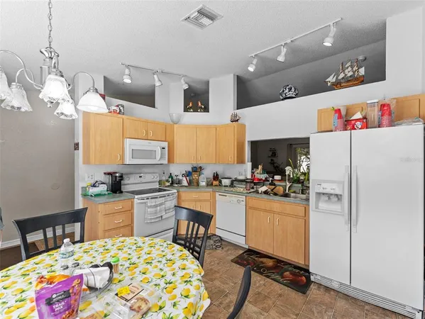 a kitchen with a refrigerator a stove a sink dishwasher with a dining table and chairs with wooden floor