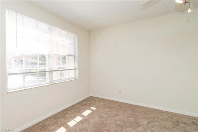 an empty room with a chandelier fan and window