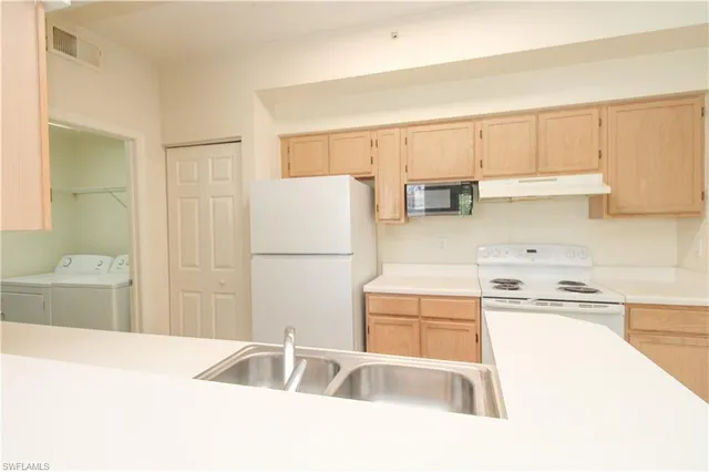 a view of washer and dryer with kitchen in the background